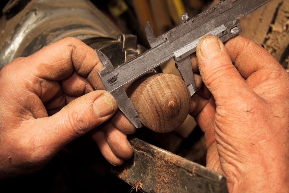 Hands measuring a turned wooden piece with calipers